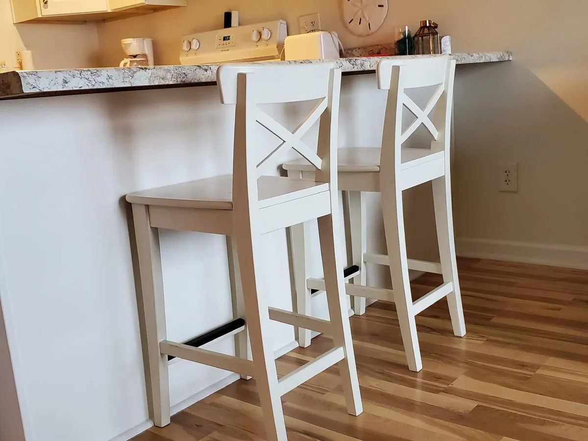 A welcoming view of the kitchen area, with bar stools lined up at a spacious countertop and modern appliances in the background. The layout encourages casual dining and social interaction.