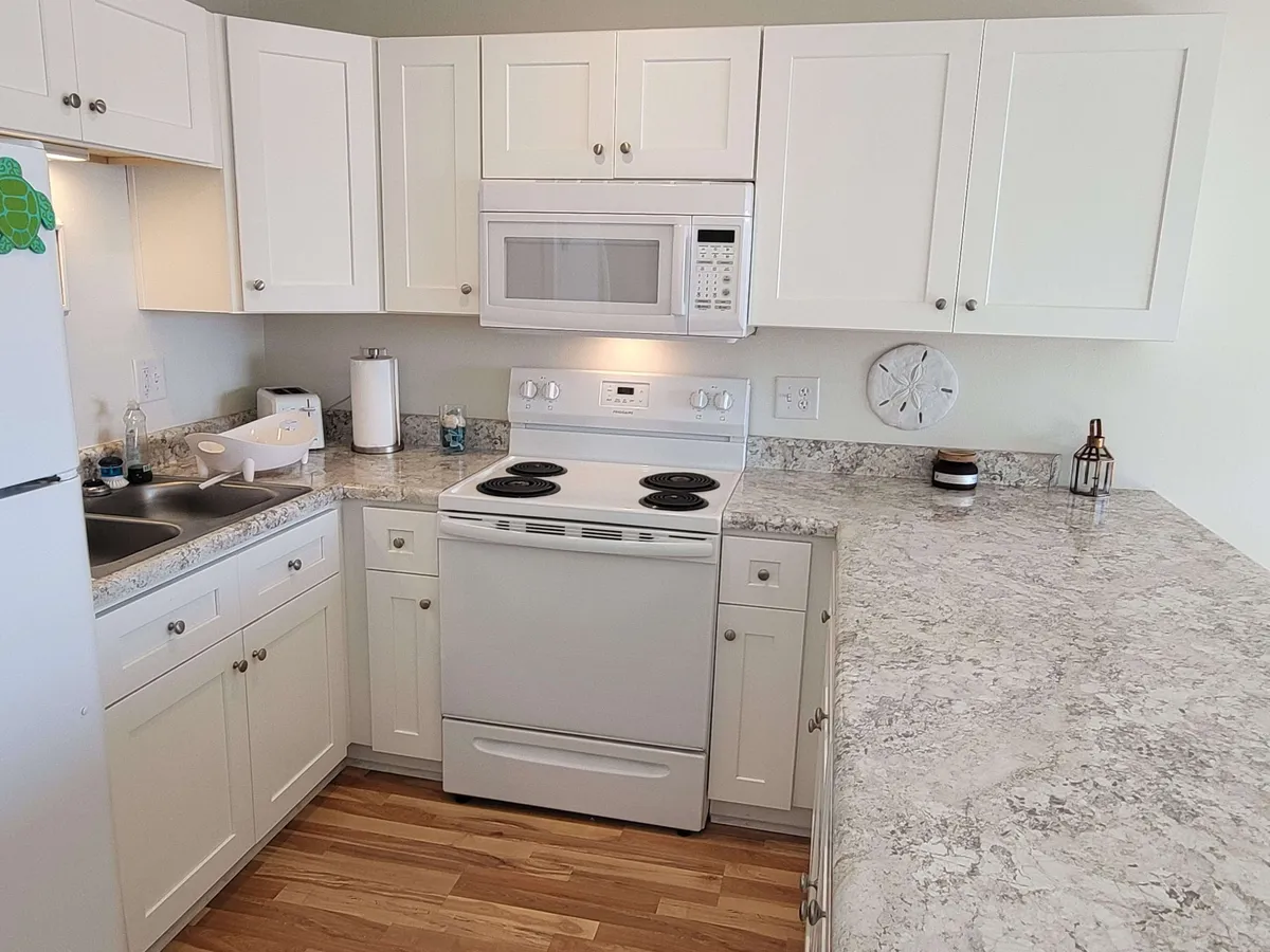 A close-up of the kitchen workspace, featuring a stove, microwave, ample countertop space, and a sink. The scene is warm and homely, perfect for preparing family feasts or intimate dinners.
