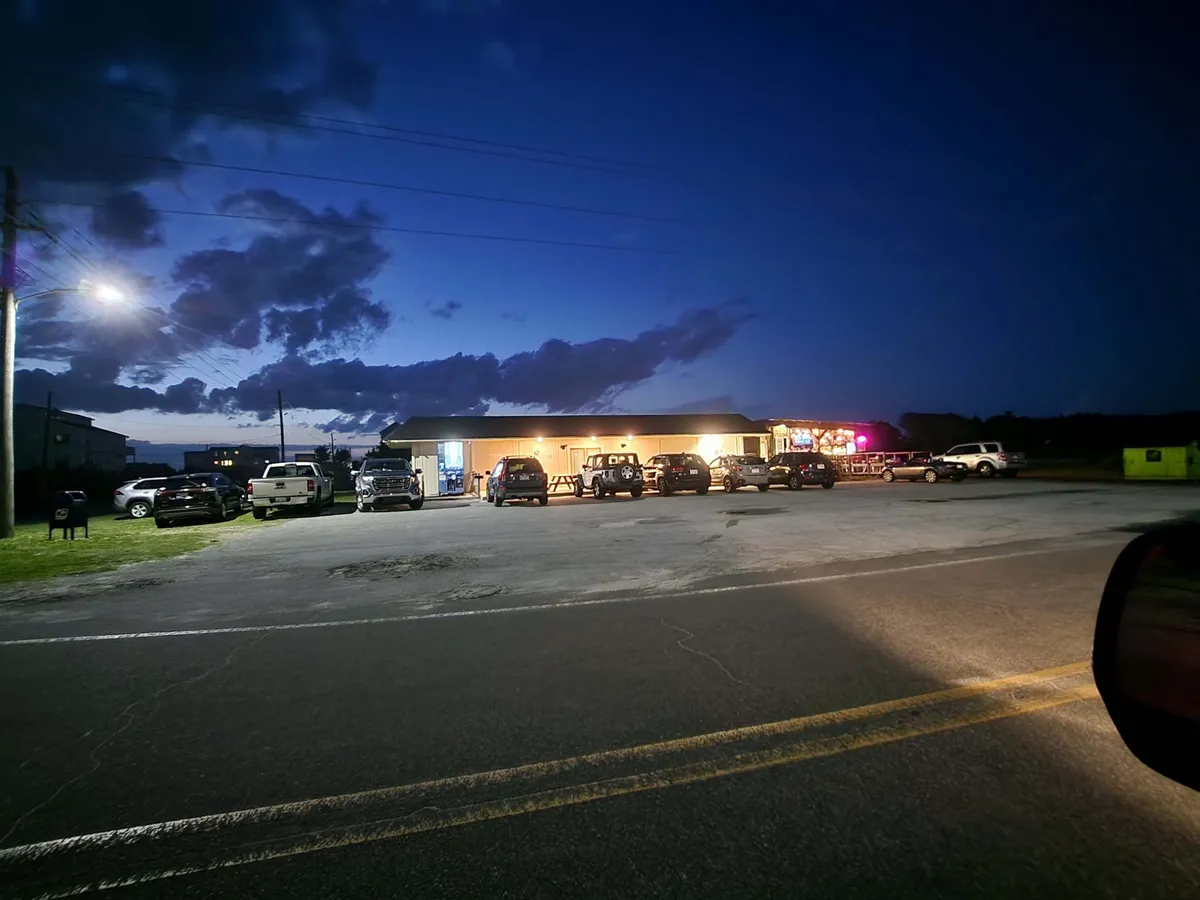 The image features a lively exterior of a nearby building with illuminated signage, cars parked out front, and a warmly lit street scene suggesting nearby dining and entertainment options.